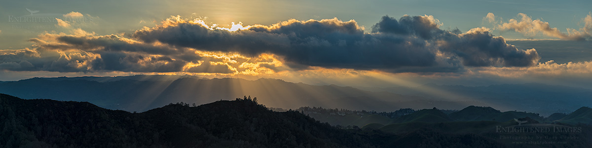 Sunlight breaking through clouds over mountain ridges